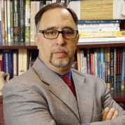 Man with dark hair, glasses and a salt-and-pepper goatee